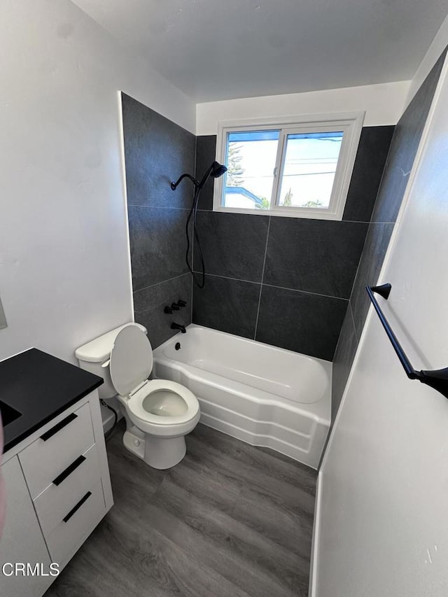 full bathroom with vanity, tiled shower / bath combo, hardwood / wood-style flooring, and toilet