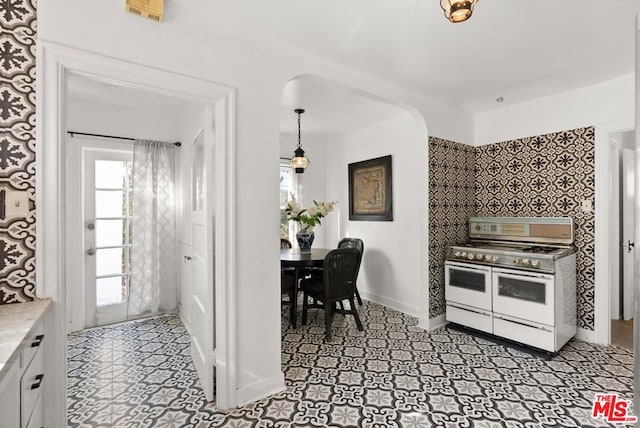 kitchen featuring white cabinets, pendant lighting, and range with two ovens