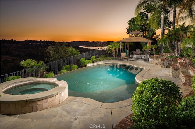 pool at dusk featuring an in ground hot tub, a gazebo, and a patio area