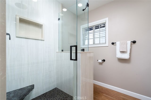 bathroom with a shower with shower door and wood-type flooring