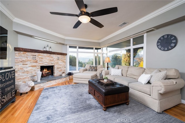 living room featuring a fireplace, hardwood / wood-style floors, ceiling fan, and crown molding