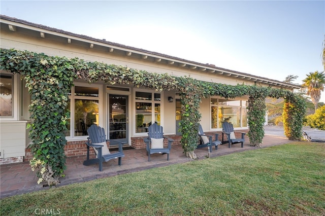 back of property featuring a lawn and a patio area