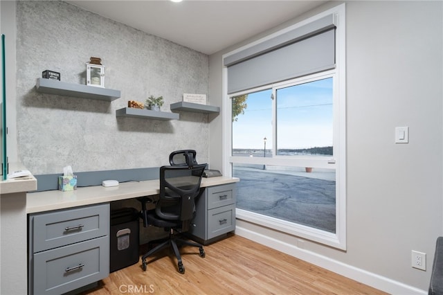 office with light hardwood / wood-style floors and a water view