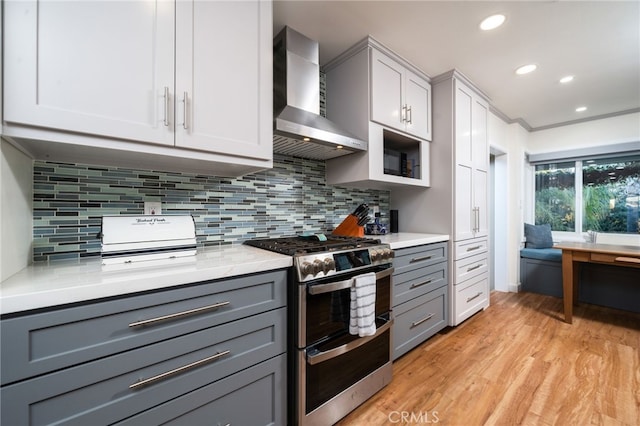 kitchen with gray cabinets, light hardwood / wood-style floors, double oven range, and wall chimney exhaust hood