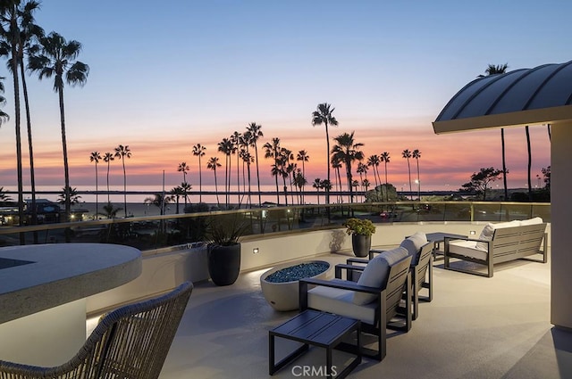 patio terrace at dusk featuring a water view and an outdoor hangout area