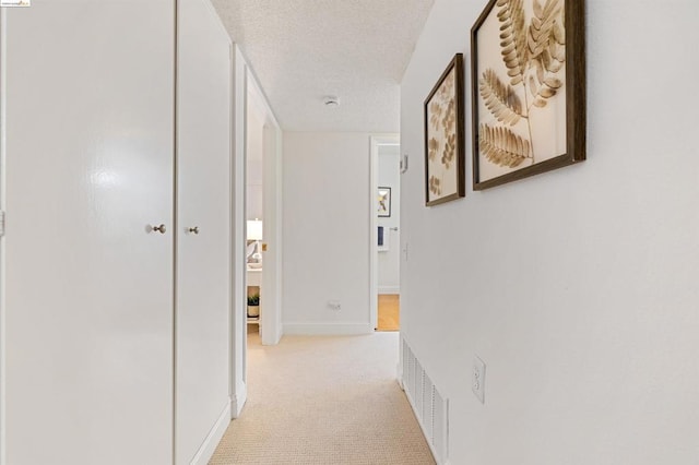 corridor featuring light carpet and a textured ceiling