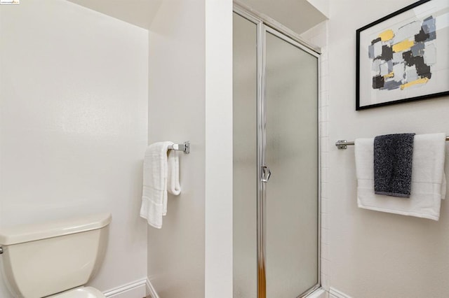 bathroom featuring toilet and a shower with shower door