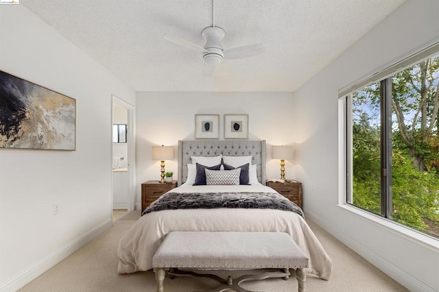 carpeted bedroom featuring ensuite bath, ceiling fan, and a textured ceiling