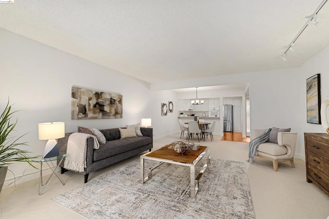 living room with light carpet, track lighting, and a notable chandelier