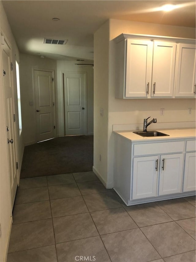 kitchen with light tile patterned floors, white cabinets, and sink