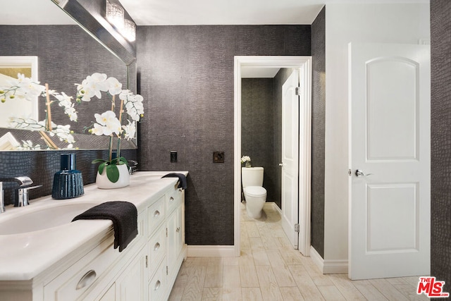 bathroom featuring wood-type flooring, vanity, and toilet