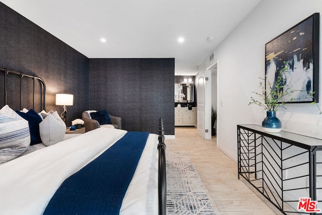 bedroom with ensuite bathroom and light hardwood / wood-style flooring