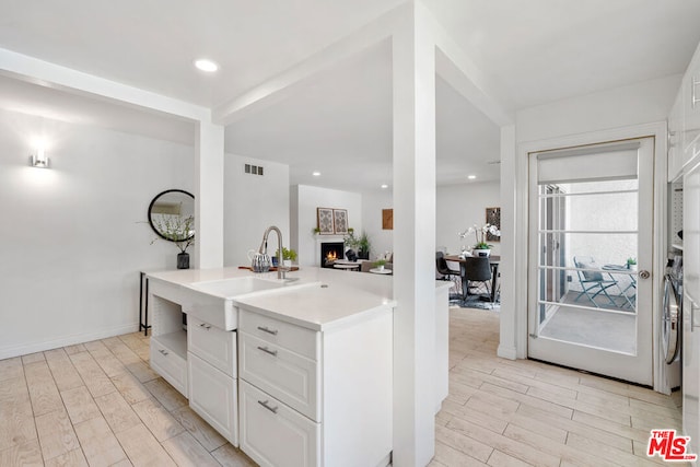 kitchen featuring sink, white cabinets, and light wood-type flooring