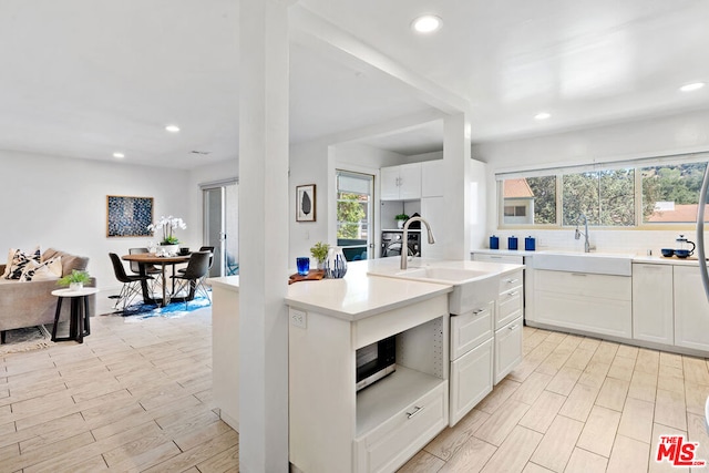 kitchen with wall oven, light hardwood / wood-style flooring, white cabinetry, and sink