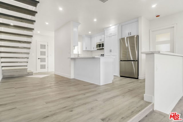 kitchen featuring white cabinets, kitchen peninsula, stainless steel appliances, and light hardwood / wood-style flooring