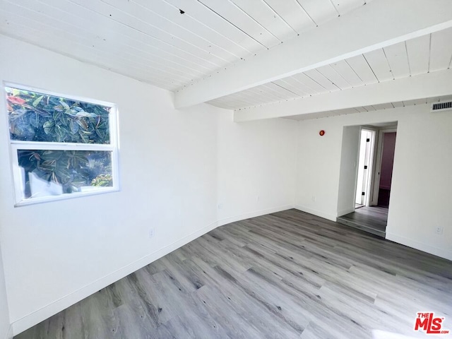 empty room with hardwood / wood-style floors and beam ceiling