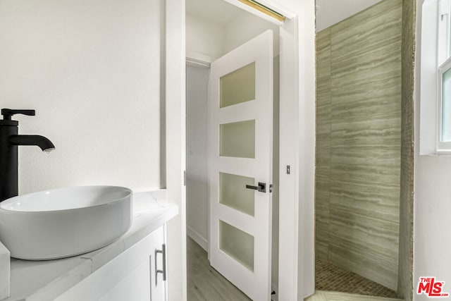 bathroom featuring tiled shower, vanity, and hardwood / wood-style flooring