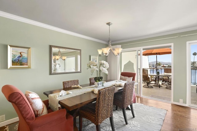 dining area featuring hardwood / wood-style floors, a notable chandelier, a water view, and crown molding