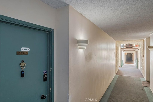 hallway with a textured ceiling and light carpet