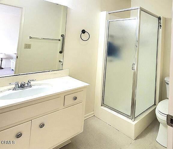 bathroom featuring vanity, toilet, and a shower with door