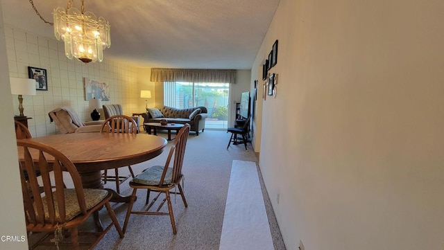 dining room featuring carpet flooring, tile walls, and an inviting chandelier