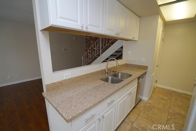 kitchen with hardwood / wood-style flooring, white cabinetry, stainless steel dishwasher, and sink