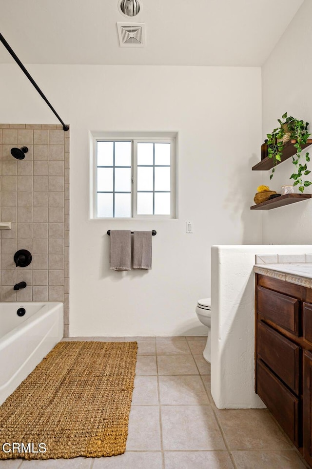 full bathroom with vanity, tiled shower / bath, tile patterned floors, and toilet