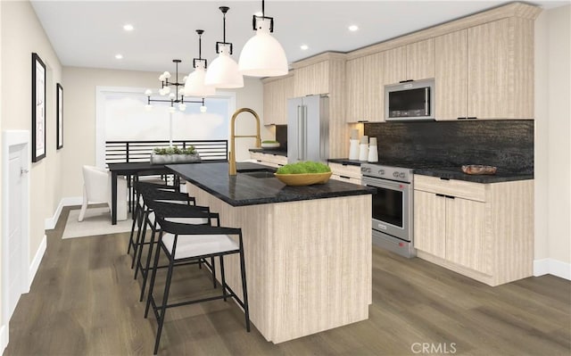 kitchen with dark hardwood / wood-style flooring, stainless steel appliances, a kitchen island with sink, sink, and pendant lighting