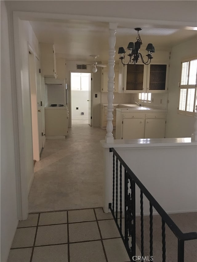 hallway featuring a chandelier, light tile patterned flooring, and sink