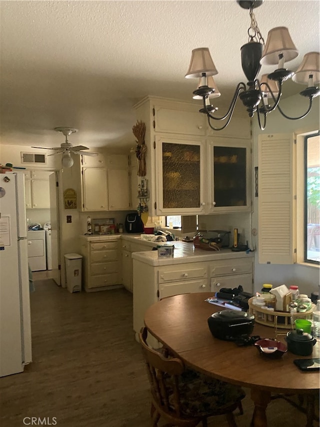 kitchen with dark hardwood / wood-style flooring, ceiling fan with notable chandelier, a textured ceiling, washing machine and dryer, and white fridge