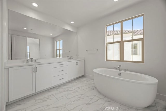 bathroom with vanity, a healthy amount of sunlight, and a bath