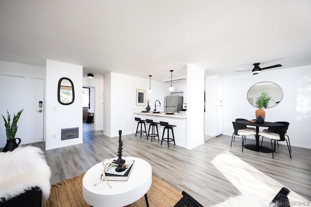 living room with sink, light hardwood / wood-style floors, and ceiling fan