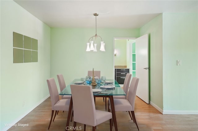 dining room with light hardwood / wood-style floors and a notable chandelier