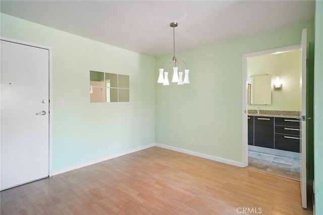 spare room with light wood-type flooring and a notable chandelier