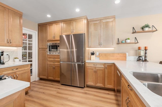 kitchen with light hardwood / wood-style floors, appliances with stainless steel finishes, light brown cabinets, tasteful backsplash, and sink