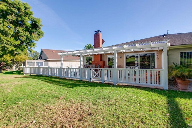 rear view of property with a pergola and a lawn