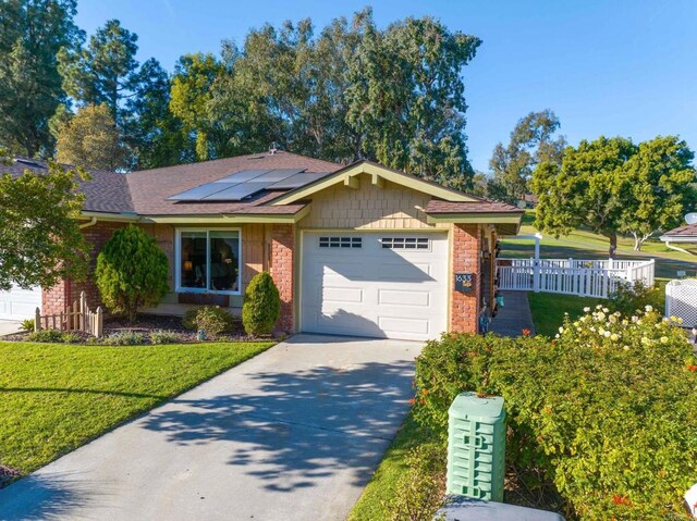 single story home featuring a garage, a front lawn, and solar panels