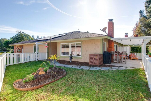 back of property featuring a lawn, solar panels, and a patio area