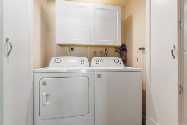 clothes washing area featuring cabinets and washer and clothes dryer