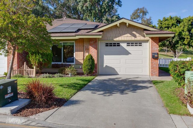 view of front of property with a garage, a front lawn, and solar panels