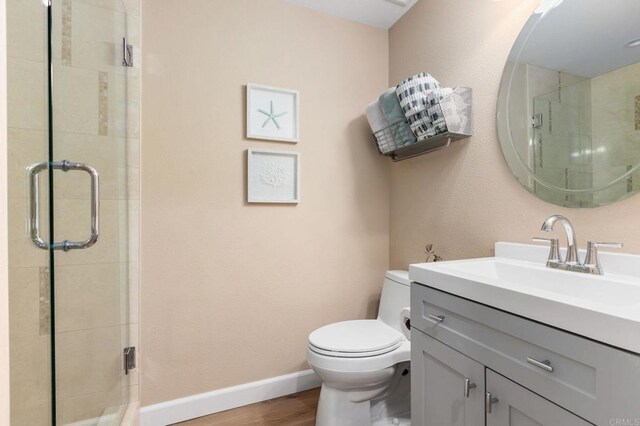 bathroom featuring vanity, an enclosed shower, hardwood / wood-style flooring, and toilet