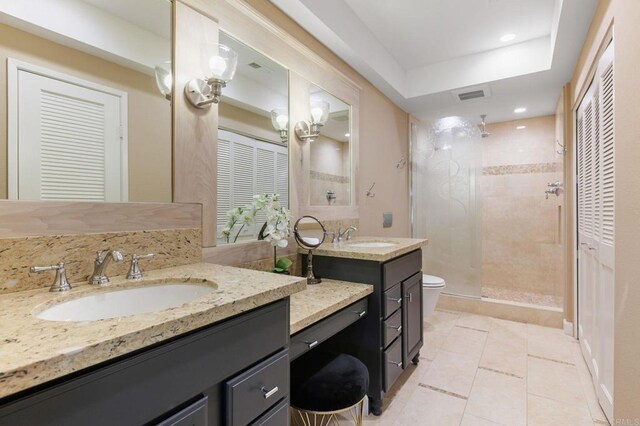 bathroom featuring vanity, a tile shower, tile patterned floors, and toilet