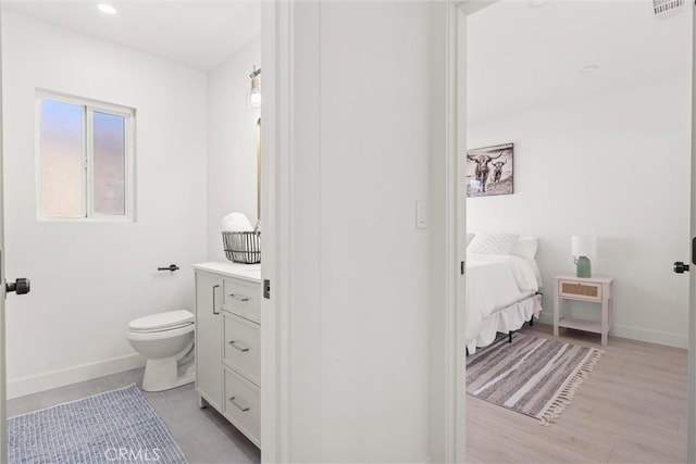 bathroom with toilet, wood-type flooring, and vanity