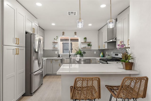 kitchen with decorative light fixtures, kitchen peninsula, appliances with stainless steel finishes, and sink