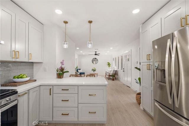 kitchen with kitchen peninsula, ceiling fan, appliances with stainless steel finishes, tasteful backsplash, and pendant lighting