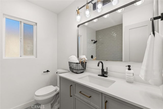 bathroom with tiled shower, vanity, and toilet