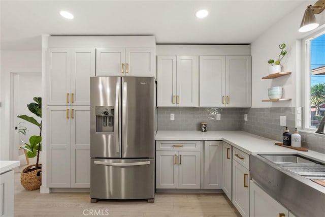 kitchen featuring light hardwood / wood-style floors, gray cabinets, stainless steel refrigerator with ice dispenser, decorative backsplash, and sink