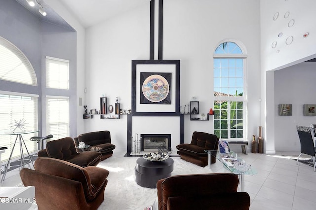 tiled living room featuring a fireplace, high vaulted ceiling, and a healthy amount of sunlight