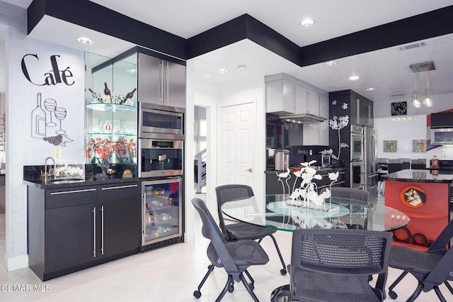 kitchen with stainless steel microwave, light tile patterned floors, beverage cooler, and sink