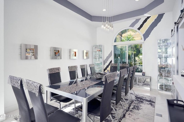 dining area with a barn door, a towering ceiling, light tile patterned floors, and a notable chandelier